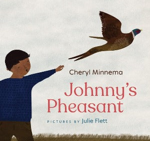 a young boy in a blue shirt is reaching upwards towards a pheasant who is flying diagonally out and up to the right