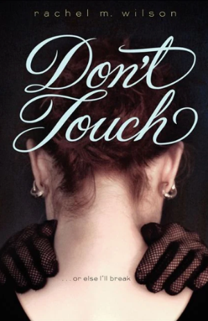a girl with white skin and auburn hair is facing away from us. You can see two hands in lace gloves on her shoulders 