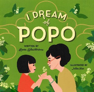 a young girl with a black hair cut in a bob is holding a blossom as her hand is held by her grandmother who has dark hair and wears glasses.