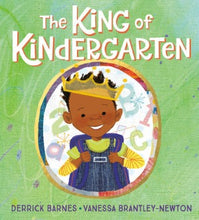 a young African American boy wearing a yellow shirt, dunagrees and a gold crown is smiling holding his backpack for school